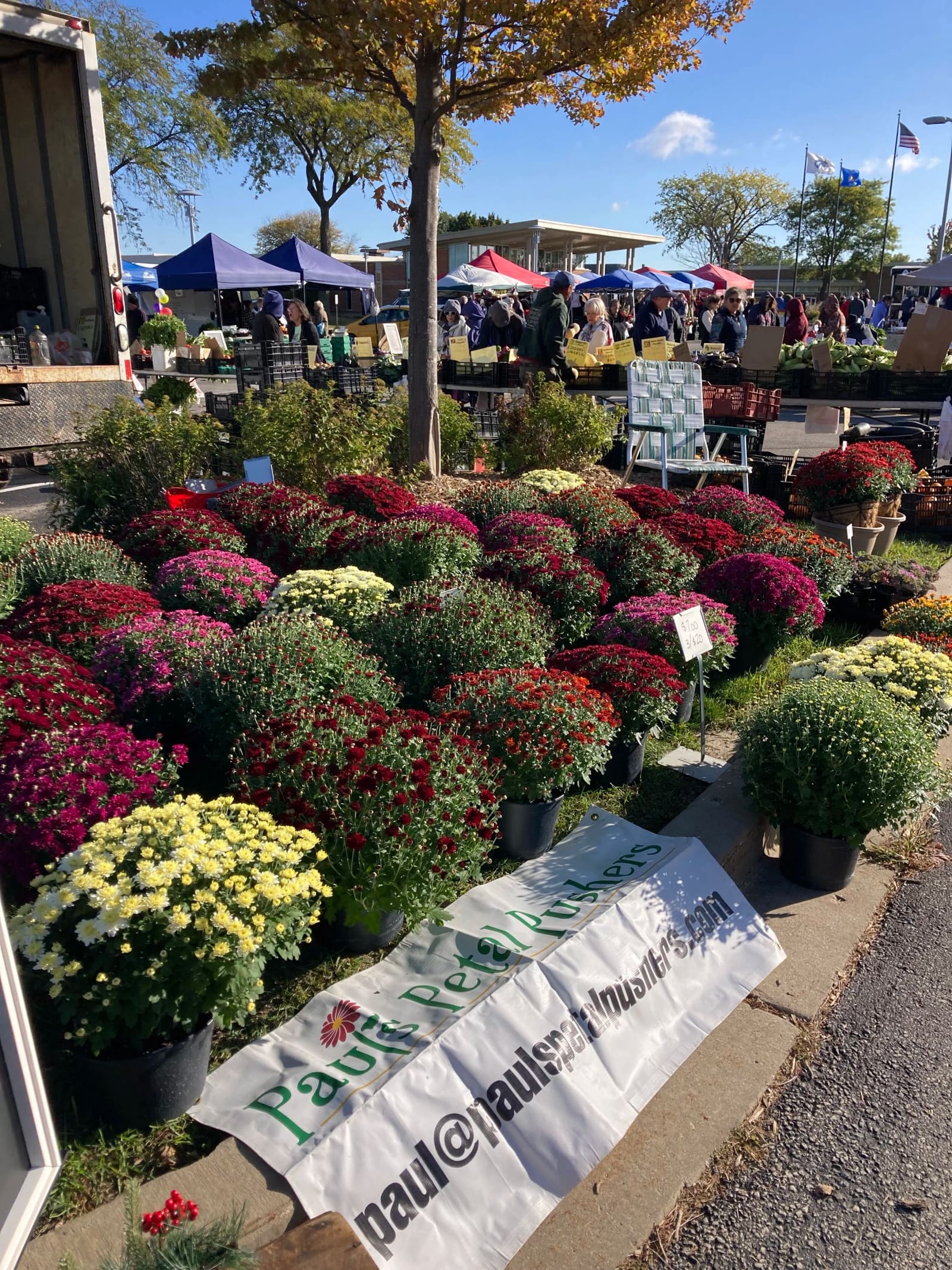 The Paul's Petal Pushers booth at the Brookfield Farmers Market in fall, stacked with mums