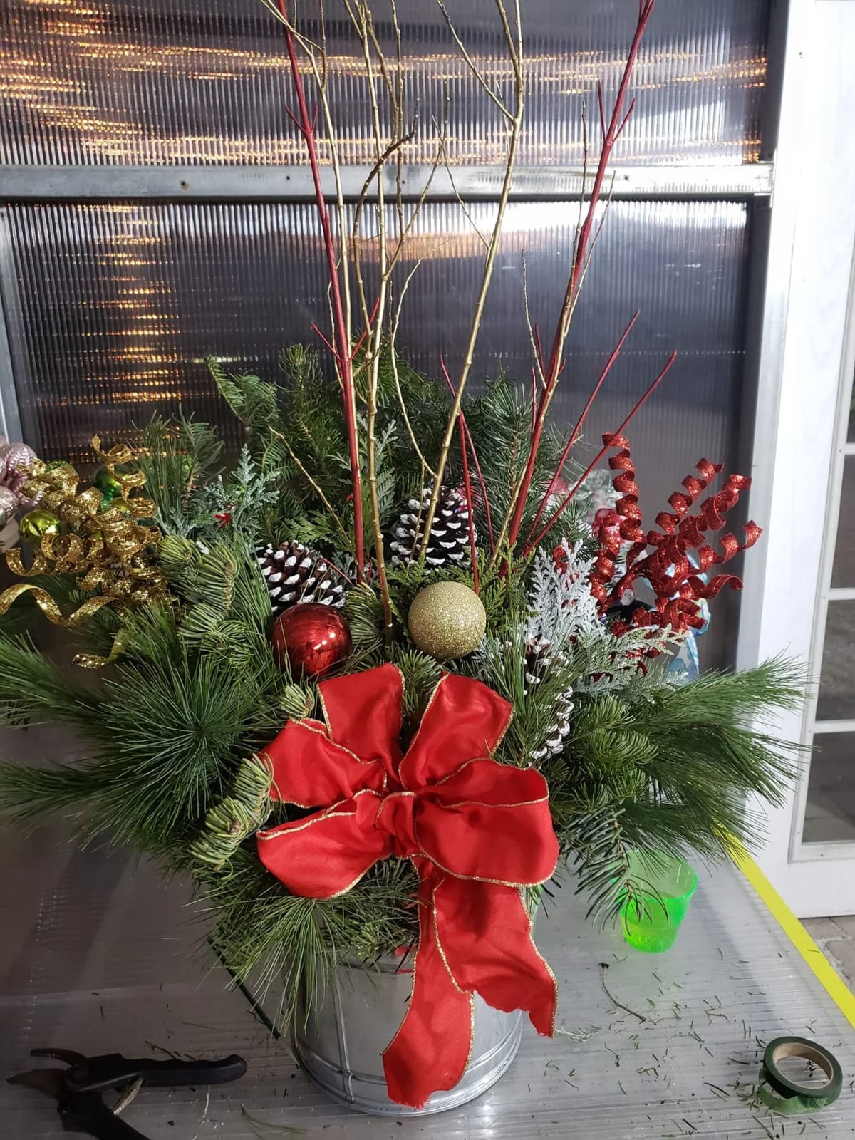 A tall evergreen Christmas container decorated with berries and ribbon