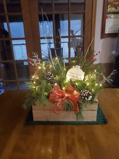 A lighted fresh evergreen Christmas container with red accents